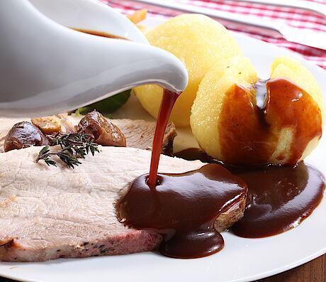 Bratensaft im Dosier mit Schweinebraten und Kartoffelknoedel